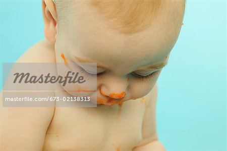 A baby with his face smeared with baby food.