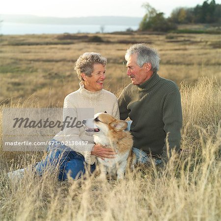 Un couple senior détente à l'extérieur avec leur chien.