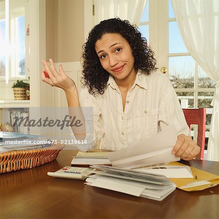 Femme exaspérée travaillant sur une pile de factures.