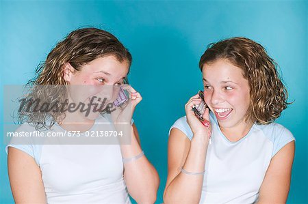 Teenaged twins with mobile phones