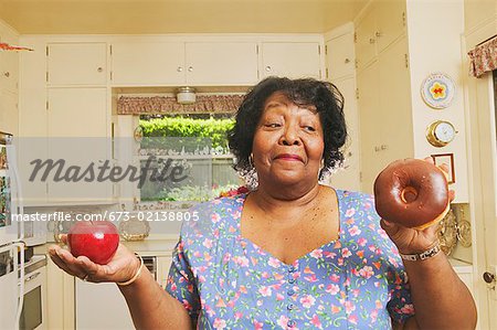 Femme de décider ou non de manger une pomme ou un beigne