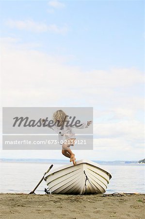 Petite fille sautant d'un bateau échoué