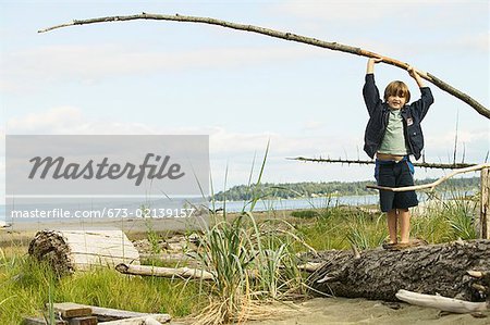 Boy playing on a log at the beach