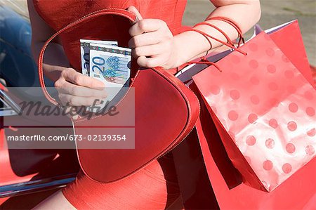 Femme tenant des euros et des sacs à provisions