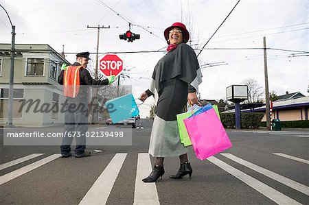 Femme avec des sacs à provisions traversant la rue
