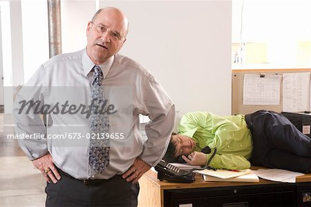 Boss discovering employee asleep on desk