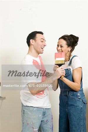 Couple playfully struggling with paintbrush