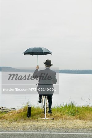 Businessman riding stationary bike by lake