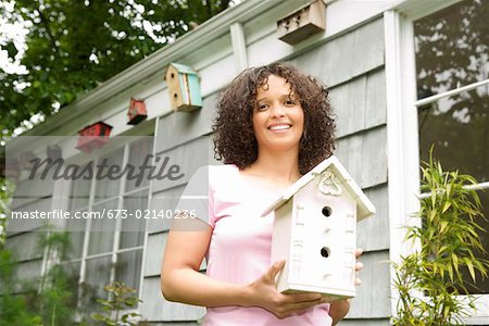 Woman outside holding birdhouse