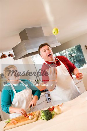 Husband juggling fruit with laughing wife