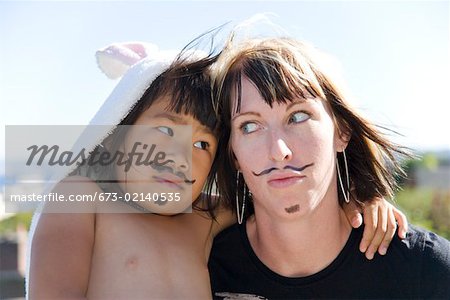 Femme enjouée et une fille avec des moustaches peintes