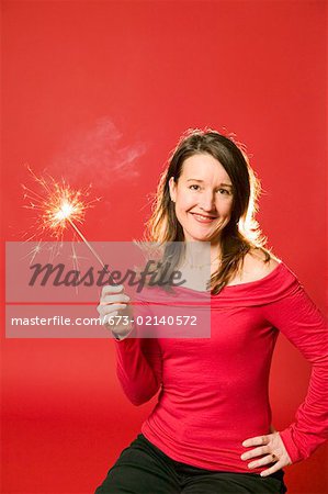 Smiling woman holding burning sparkler