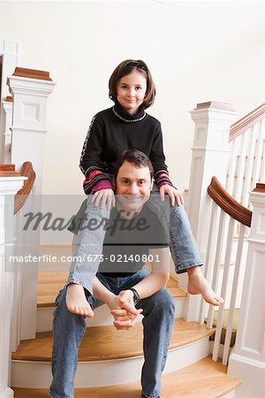 Daughter sitting on dads shoulders on stairs