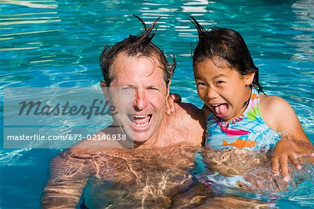 Portrait of father and daughter being silly in pool