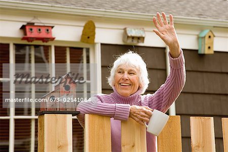 Senior woman waving over fence