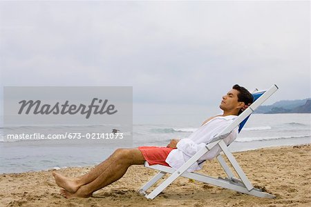Mann schlafen im Stuhl am Strand