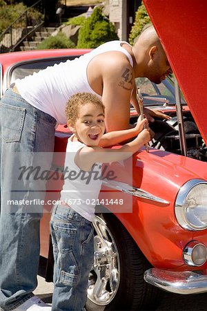 Young boy holding tools for his mechanic father
