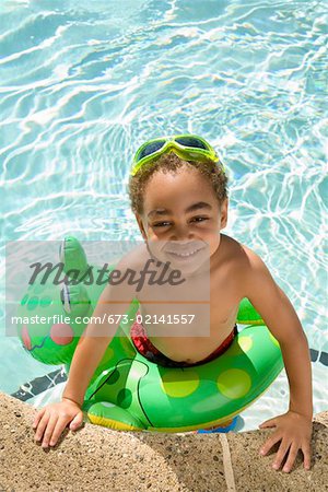 Young boy wearing a flotation device in pool