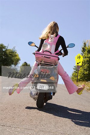 Woman riding a scooter with extended legs