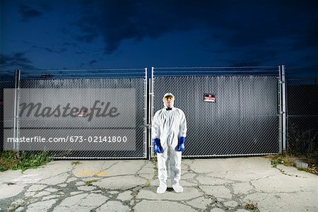 Man in biohazard suit standing outside security gate