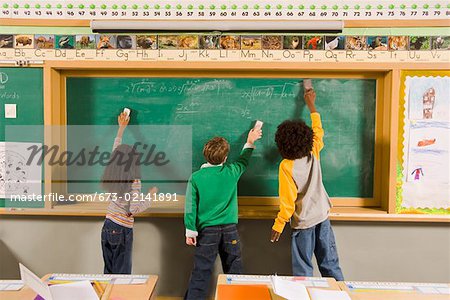 Children erasing blackboard in classroom