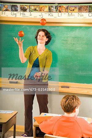 Female teacher juggling apples in classroom