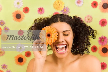 Woman laughing and holding flower over eye