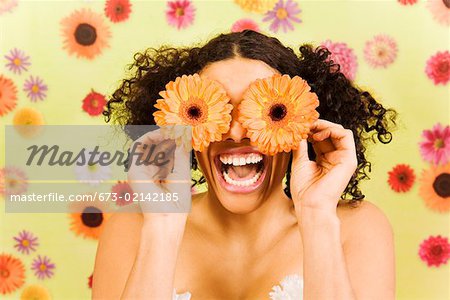 Femme riant et tenant des fleurs sur les yeux