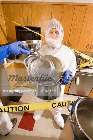 Man wearing coveralls and holding pots in dirty kitchen