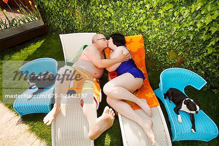 Couple kissing on lawn chairs in backyard