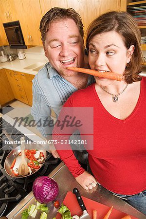 Couple playing with food while cooking