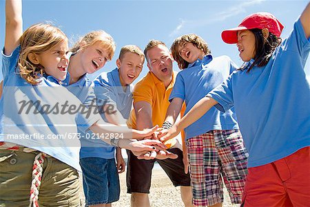 Male camp counselor with children in huddle