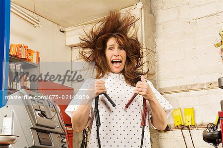 Woman in hospital gown holding jumper cables