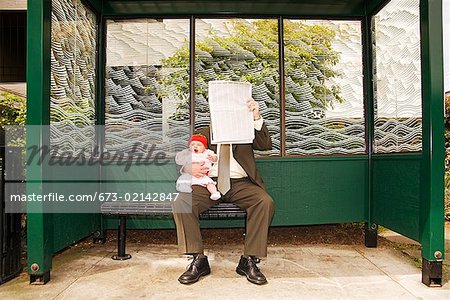 Businessman holding baby at bus stop
