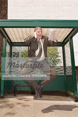 Businessman jumping at bus stop