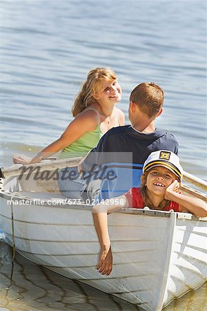Boy and girl in row boat with young sibling