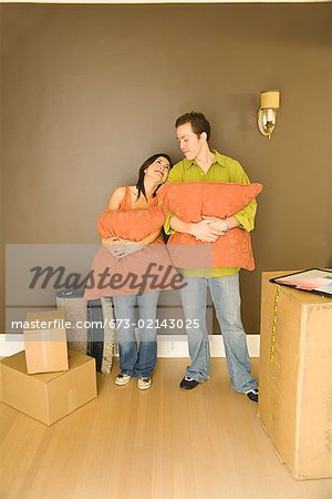 Couple hispanique Étreintes Oreillers dans maison neuve