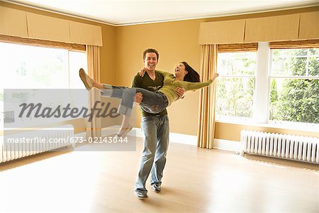 Hispanic man carrying wife in new house