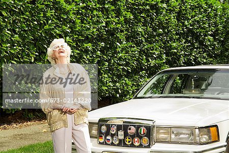 Senior woman laughing next to car