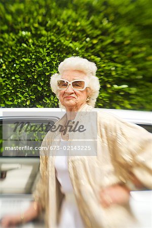 Senior woman standing next to car
