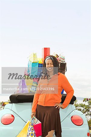 African woman next to convertible with shopping bags