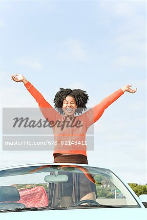 Afrikanerin mit Arme heben in Cabrio Auto