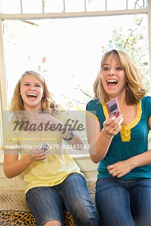 Sœurs adolescentes rire avec les téléphones cellulaires