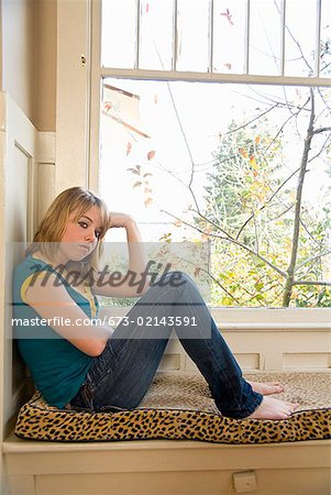 Teenaged girl sitting next to window