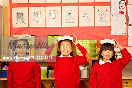 Multi-ethnic girl balancing school books on heads