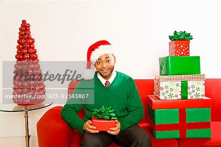 African man next to stack of Christmas gifts