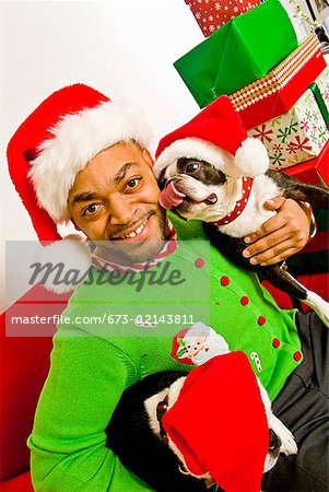 African man and dogs wearing Santa Claus hats