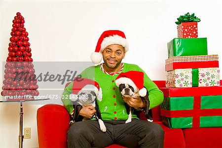 African man and dogs wearing Santa Claus hats