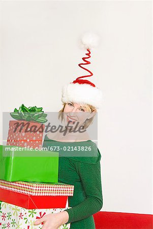 Woman carrying stack of Christmas gifts