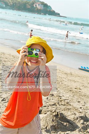 Asian girl taking photograph at beach